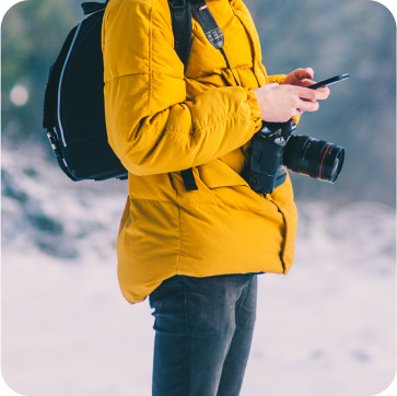 male in yellow puffer jacket, camera and mobile phone