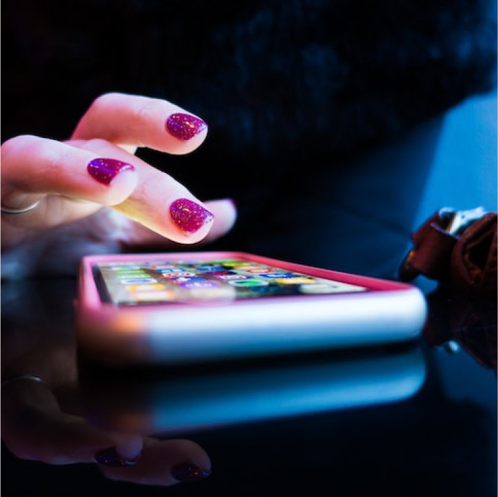 woman's hand with purple nails and mobile phone